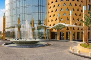 JW Marriott Hotel Riyadh في الرياض: نافورة امام مبنى به مبنى