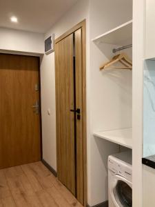 een wasruimte met een deur en een wasmachine en droger bij Apartament 221 przy Niedźwiadku in Polanica-Zdrój