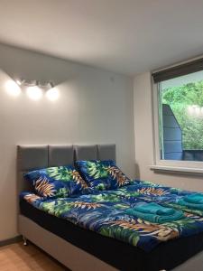 a bed in a room with a window and a bed with colorful sheets at Apartament 221 przy Niedźwiadku in Polanica-Zdrój