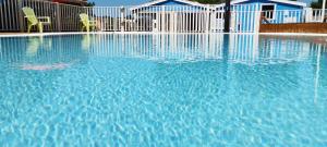 a swimming pool with blue water and two chairs at CAMPING LES EMBRUNS 3* in Camoël +48 photos