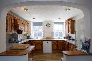 a kitchen with wooden cabinets and a clock on the wall at Lamack Vale House, Tenby, 5 Bedrooms with Private Heated Indoor Swimming Pool & Parking in Tenby