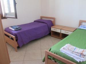 a bedroom with two beds with purple sheets at White House in Tre Fontane