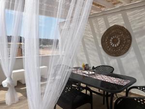 サン・ヴィート・ロ・カーポにあるsicily home casa vacanze con piscinaのカーテン付きの部屋(テーブル、椅子付)