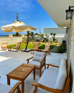 eine Terrasse mit Stühlen, einem Tisch und einem Sonnenschirm in der Unterkunft Vahide Dalyan in Cesme