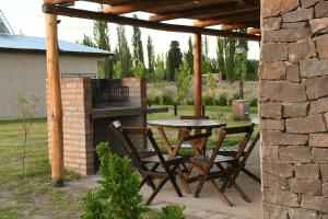 un patio con mesa, sillas y parrilla en Cabañas Viento Andino en San Rafael