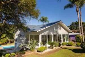 a white house with a swimming pool and palm trees at Casa Garavaglia in Bento Gonçalves