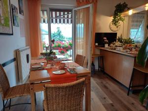 a dining room with a table with chairs and a kitchen at Il Geranio B&B in Rovereto