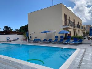 サン・ヴィート・ロ・カーポにあるsicily home casa vacanze con piscinaの建物の隣にスイミングプール(椅子、パラソル付)