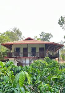a house with a balcony in a field of crops at THE MASCARA - Home stay @ Coorg in Kushālnagar