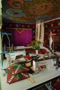 Zimmer mit einer Nähmaschine und einem Tisch mit Decken in der Unterkunft House of Tengi Craftswomen 