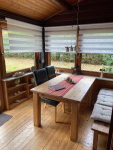 einen Holztisch und Stühle in einem Zimmer mit Fenstern in der Unterkunft Blockhaus FerienZauber in Bromskirchen