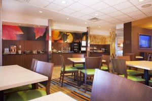 um restaurante com mesas de madeira e cadeiras verdes em Fairfield Inn & Suites by Marriott Lethbridge em Lethbridge