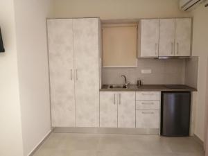 a kitchen with white cabinets and a stainless steel refrigerator at Dafni studios no8 in Parga