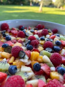 a bowl of fruit salad with raspberries and blueberries at Le 36 Maison d'hôtes Piscine & Spa in La Flotte