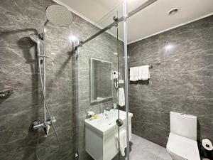 a bathroom with a shower and a toilet and a sink at Garnet Hotel Tashkent in Tashkent