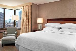 a hotel room with a bed and a chair and a window at Sheraton Centre Toronto Hotel in Toronto