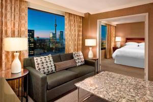 a hotel room with a couch and a bed and a window at Sheraton Centre Toronto Hotel in Toronto