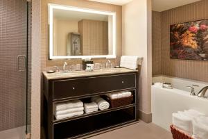 a bathroom with a sink and a mirror and a tub at Sheraton Centre Toronto Hotel in Toronto