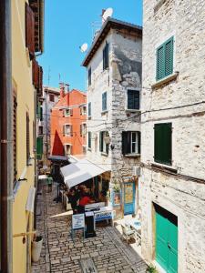 an alley in an old town with a person sitting under an umbrella at Apartment Casa Nova in Rovinj