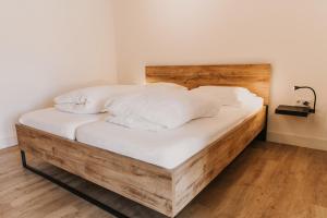 ein Holzbett mit weißer Bettwäsche und Kissen in der Unterkunft Appartement Wadpier in Buren