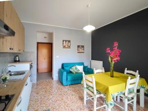 eine Küche und ein Wohnzimmer mit einem gelben Tisch und einem blauen Sofa in der Unterkunft Sole Paola in Anzio