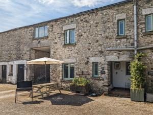 a table and an umbrella in front of a stone building at The Coach House - Uk38044 in Beetham