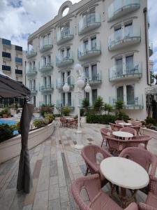 a hotel with tables and chairs in front of a building at Hotel Ambassador in Rimini