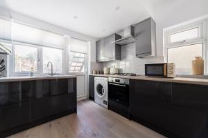 a kitchen with black cabinets and a washer and dryer at The Neasden Villas in London