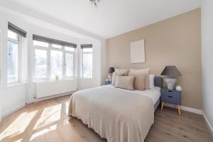 a white bedroom with a large bed and windows at The Neasden Villas in London