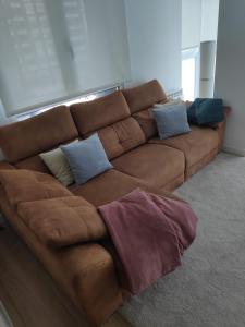 a brown couch with pillows in a living room at Precioso apartamento recién reformado in Gijón