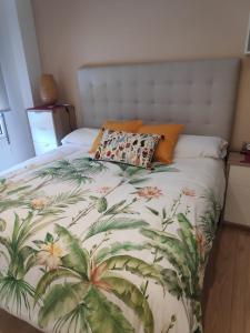 1 dormitorio con 1 cama con colcha tropical en Precioso apartamento recién reformado en Gijón