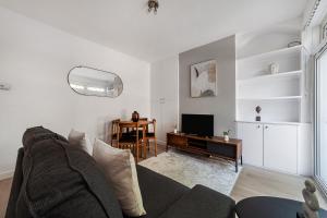 een woonkamer met een bank en een televisie bij The Neasden Villas in Londen