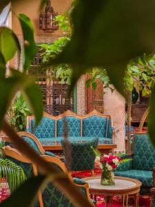 Zimmer mit blauen Sofas und einem Tisch mit Blumen in der Unterkunft DAR CHIBANIA in Marrakesch