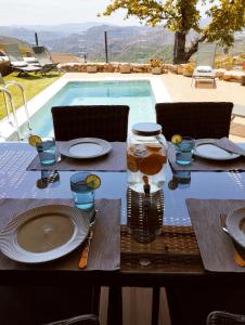 a table with plates and glasses next to a swimming pool at Pitões NatureHouse in Pitões das Júnias