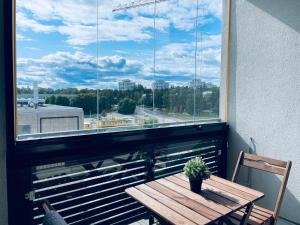 a wooden table with a potted plant on a balcony with a window at Tapiola City Apartment in Espoo