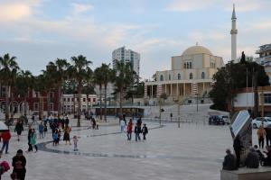 a group of people walking around a plaza at ~Villa Gloria~ in Durrës