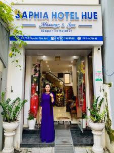 a woman standing in front of a hotel at Sapphire Hotel Hue in Hue