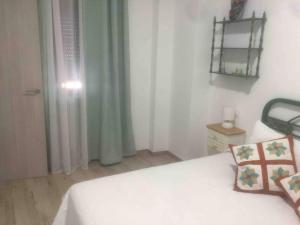 1 dormitorio con cama blanca y ventana en La casita Ossa, en Ossa de Montiel