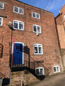 ein Backsteingebäude mit einer blauen Tür und einem Balkon in der Unterkunft Zeppelin House - Riverside 18th Century Townhouse in Bewdley