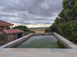 una piscina de agua en un patio con una casa en El encinar de Gabino, en Zarzuela del Monte