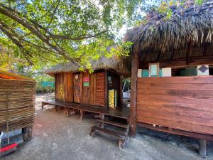 Balam Camping & cabañas في جزيرة هول بوكس: كوخ صغير بسقف من القش ومقعد