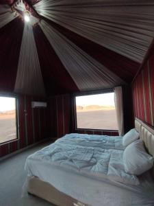 a large bed in a tent with two windows at Wadi rum Sunrise luxury camp in Wadi Rum