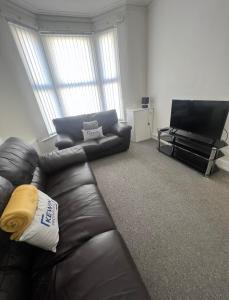 a living room with a leather couch and a flat screen tv at Large 3 bed - 10 mins to centre in Liverpool