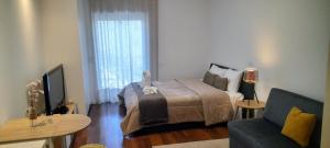 a bedroom with a bed and a couch and a television at Ria Palace Apartment in Aveiro