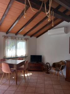 sala de estar con mesa, sillas y TV en Mansarda con terrazza a Diano en Diano Castello