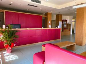 una sala d'attesa con parete rosa di Hotel Grecale - Venturina Terme a Venturina Terme