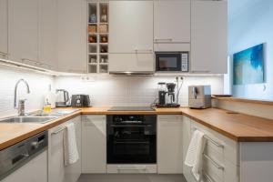 a kitchen with white cabinets and a black appliance at Luxury Design Gem in City Center with Sauna and workspace in Helsinki