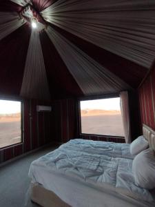 a large bed in a room with two windows at Wadi rum Sunrise luxury camp in Wadi Rum