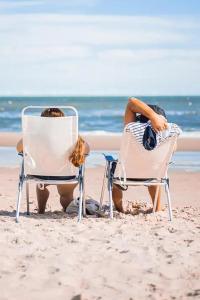Dos personas sentadas en sillas en la playa en CAMPING LE COTE D'OPALE en Cucq