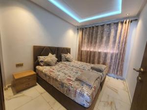 een slaapkamer met een bed in een kamer met een raam bij Cosy Appartement meublé à Mehdia in Kenitra